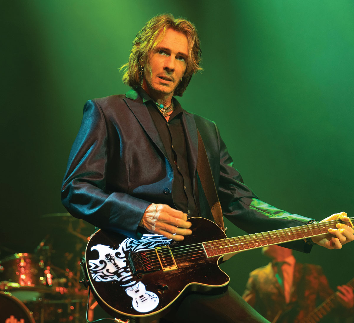 A photo of the musician Rick Springfield on stage at a concert playing electric guitar. Rick Springfield will be a performer at the 2024 Dutchess County Fair.